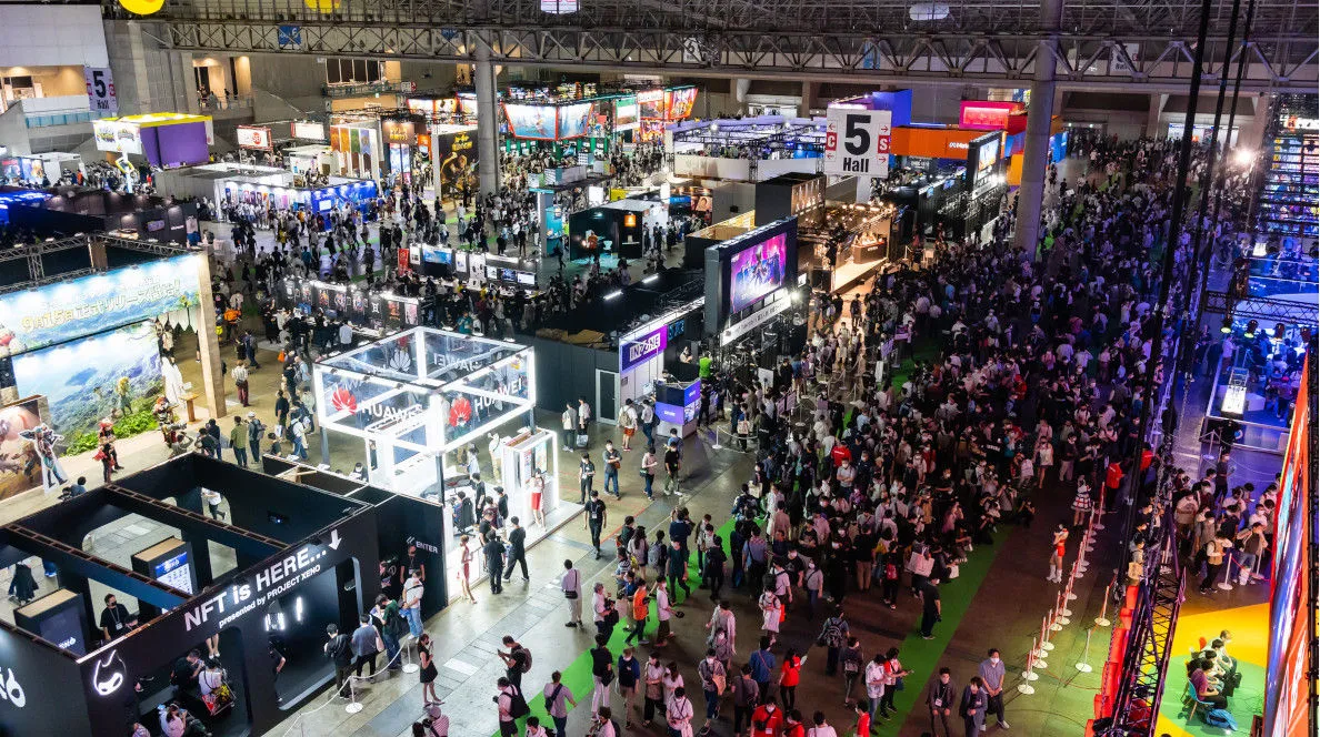 The Tokyo Game Show floor at Makuhari Messe, looking across publisher booths and crowds toward the Hall 5 signage, at a previous edition