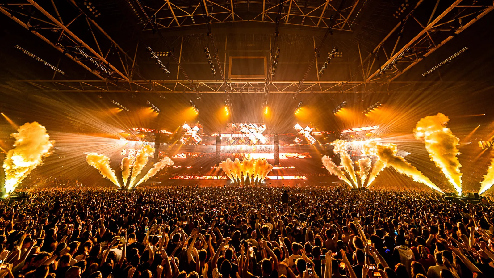 A packed arena crowd in front of a lit stage with pyrotechnics, of the kind that fills Amsterdam's venues during ADE