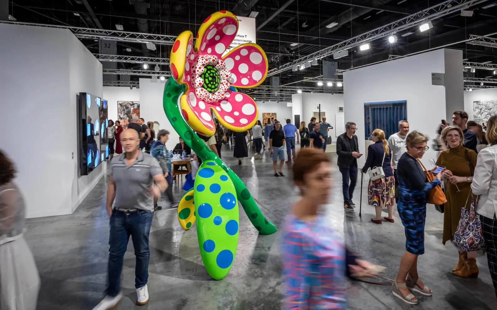Gallery booths and a large polka-dot flower sculpture on the Art Basel fair floor at a previous edition